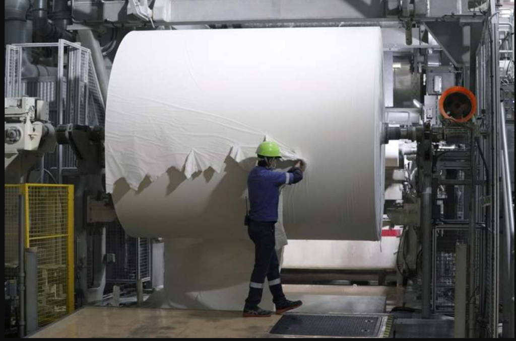 A worker checks a spool of recycled paper on the toilet paper production line at a Corelex Shinei Co. factory in Fuji, Shizuoka Prefecture, Japan, on Sept. 7, 2021