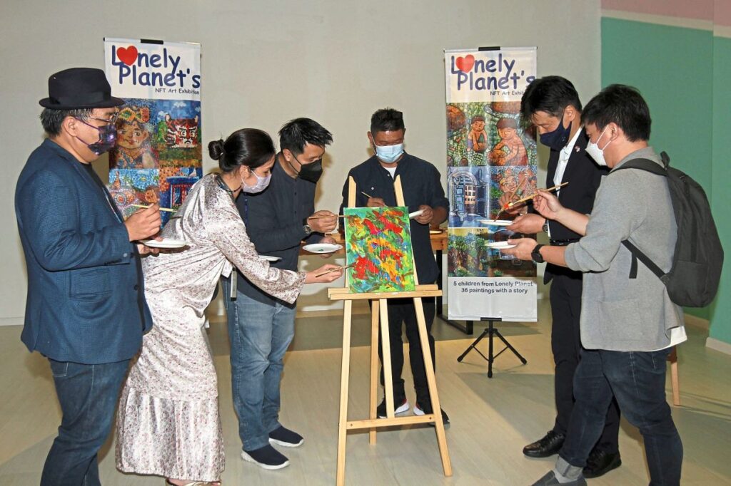 Lai (third from right) and Lau (right) joining other project partners and supporters in daubing paint on a canvas to launch the art exhibition at GMBB Mall in Bukit Bintang. — Photos: CHAN TAK KONG/The Star